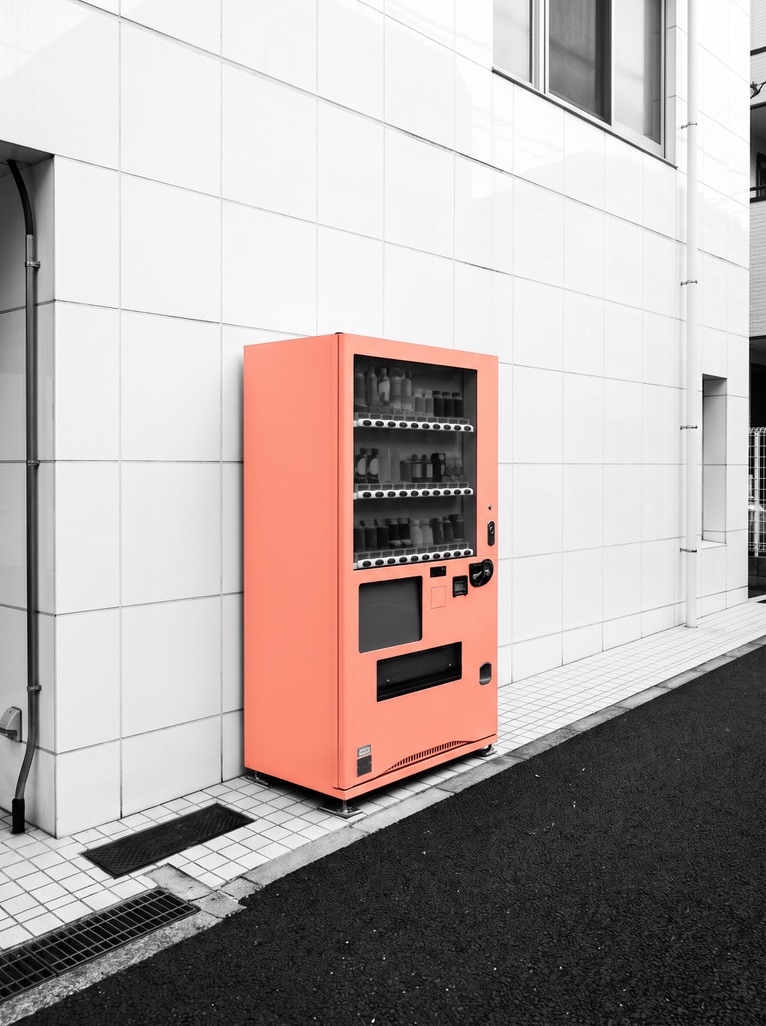Peach vending machine against a white tiled wall