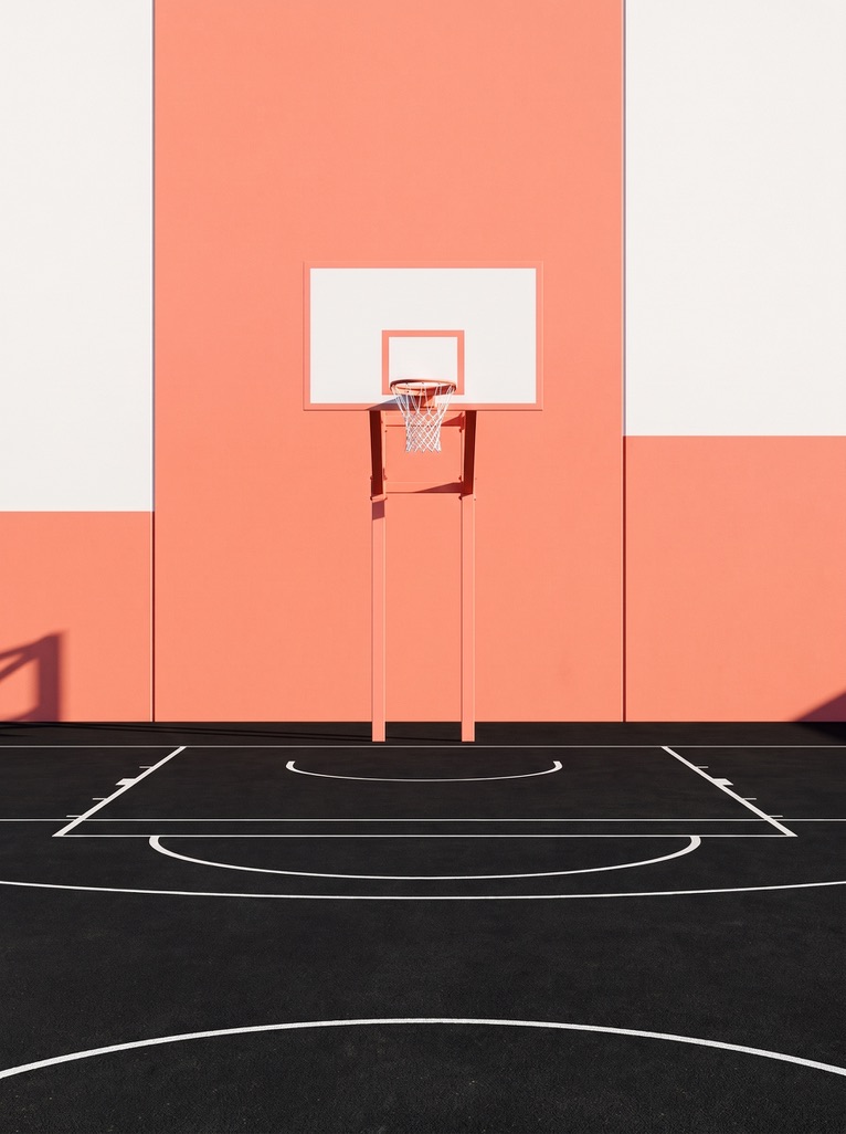 Basketball hoop on a peach wall above a black court
