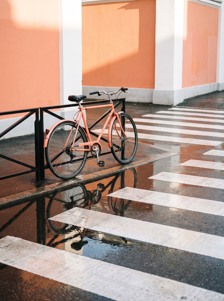Peach bicycle beside a striped crossing on a wet terrace